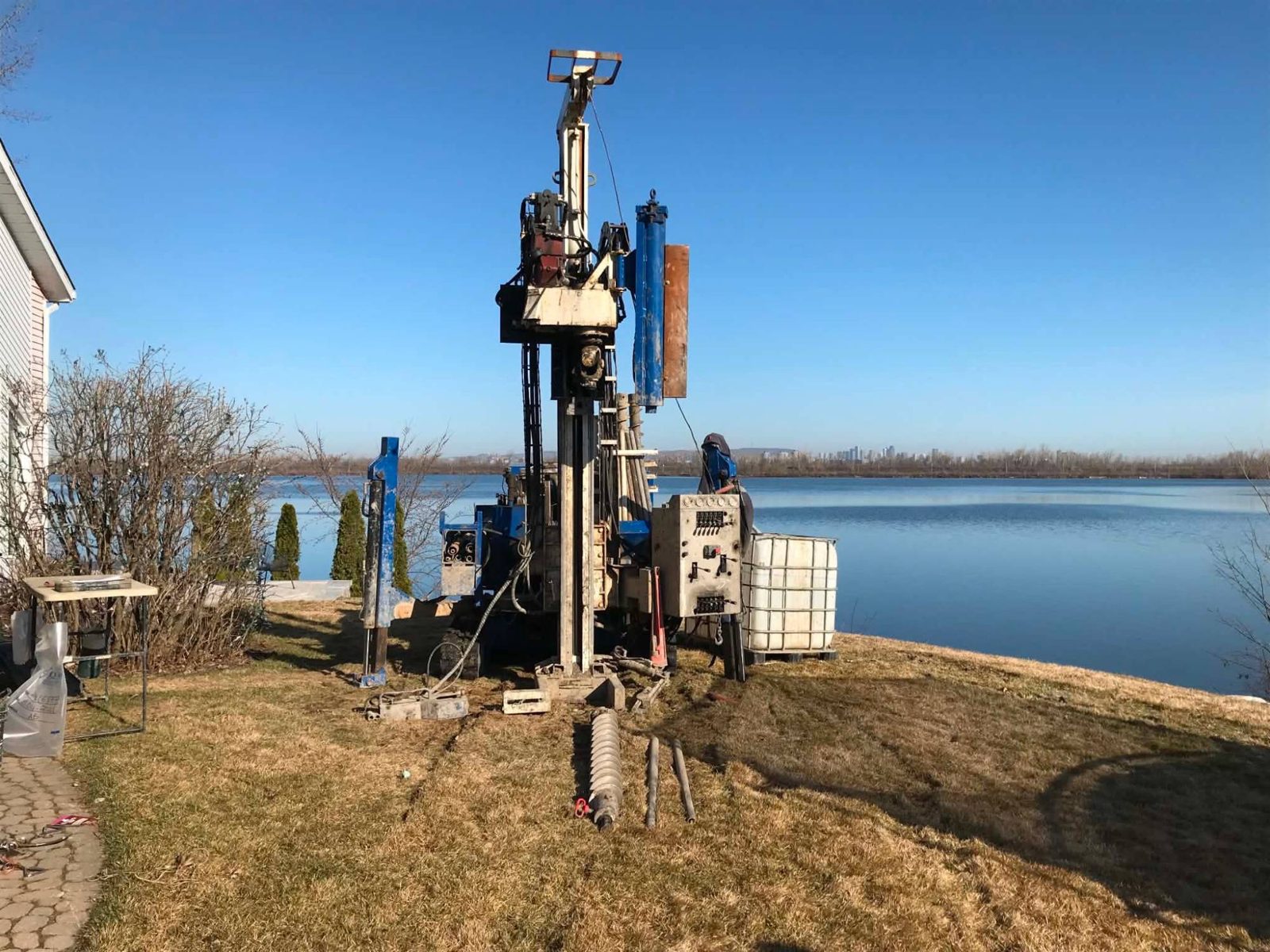 Foreuse des Forages GG installée sur un terrain au bord de l'eau, la ville à l'horizon