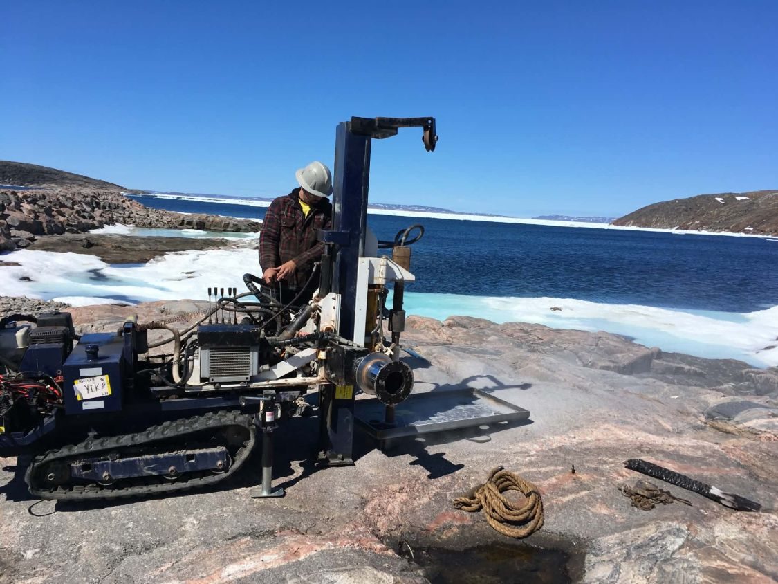 Un foreur des Forages GG aux commandes d'une foreuse compacte, sur le roc au bord de la mer